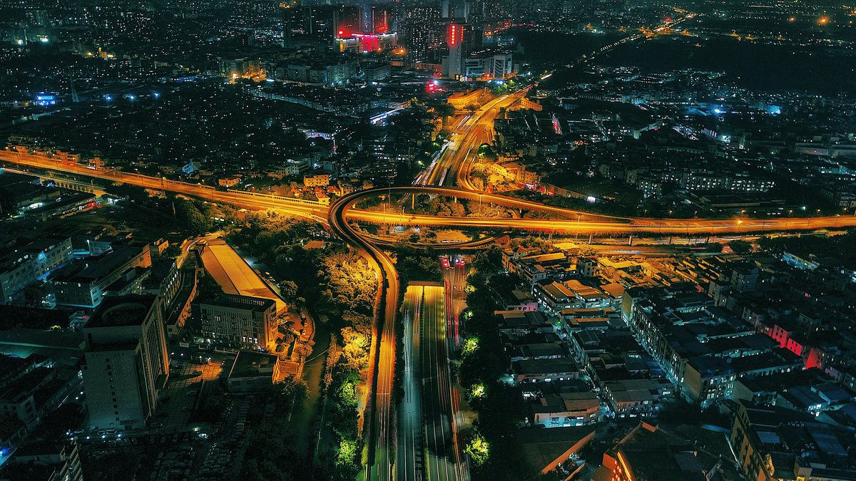 Vista aérea nocturna de un intercambiador urbano rodeado de tejido residencial denso